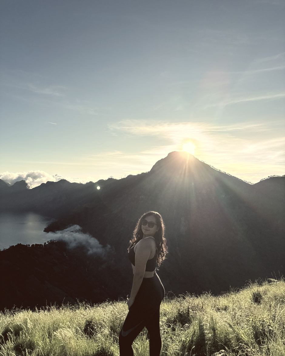 The founder standing on a ridge above the Rinjani crater lake as the sun breaks over the peak.